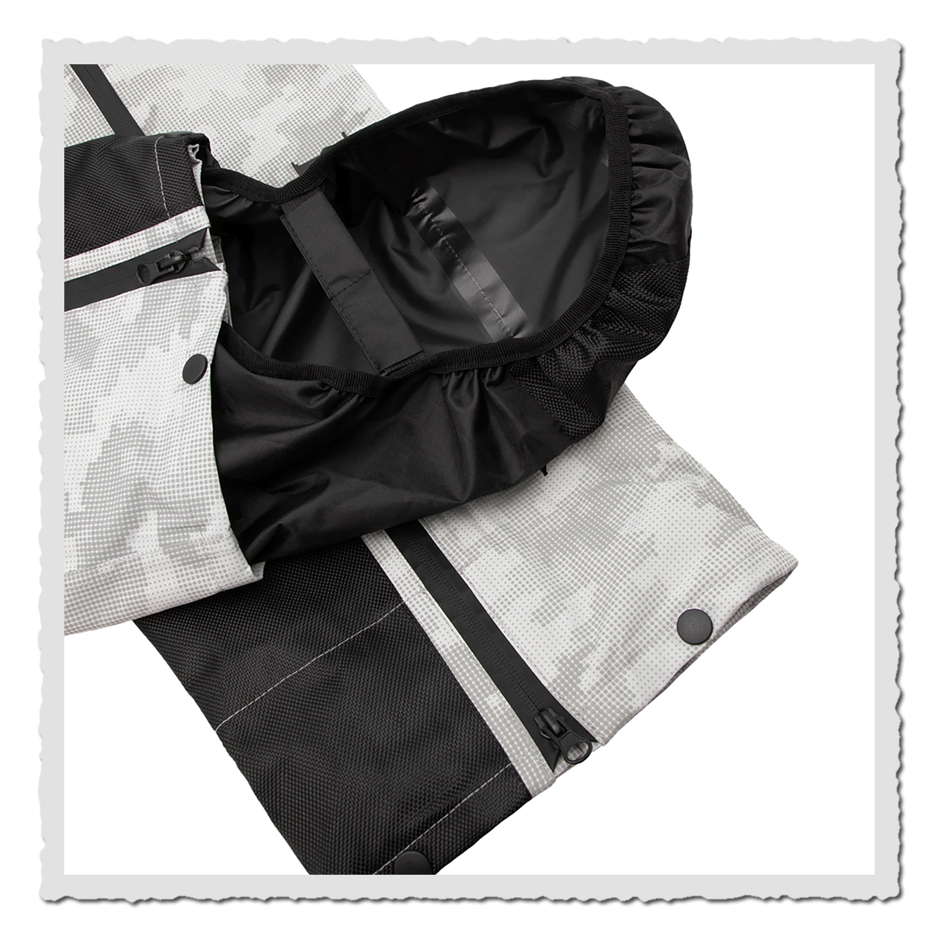 Nahaufnahme grau-weisse Hosenbeinabschluss mit Stiefelschutz, Camoflage-Stoff und Druckknöpfe sichtbar.